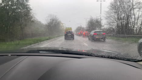 driving in a heavy rain storm in a traffic jam on the road in england with the windscreen wipers clearing the rainfall