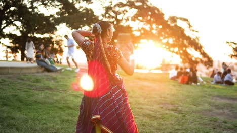 south asian woman performing classical indian dance during sunset in the park garden in sydney, australia