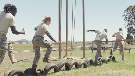 diverse group ale soldiers running on car tyres at army obstacle course in the sun