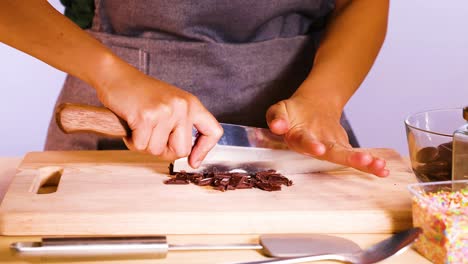 person chopping chocolate discs with a knife