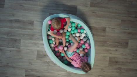 Cheerful-toddler-and-preschooler-play-lying-in-dry-pool