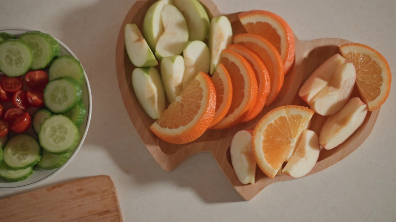 Sequenza in cucina dall'alto che mostra due ciotole su un piano di lavoro beige, dove l'azione visibile è la disposizione e il riposizionamento di fette di frutta e verdura.