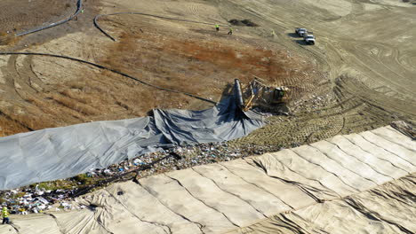 aerial view of landfill operations with heavy machinery and workers