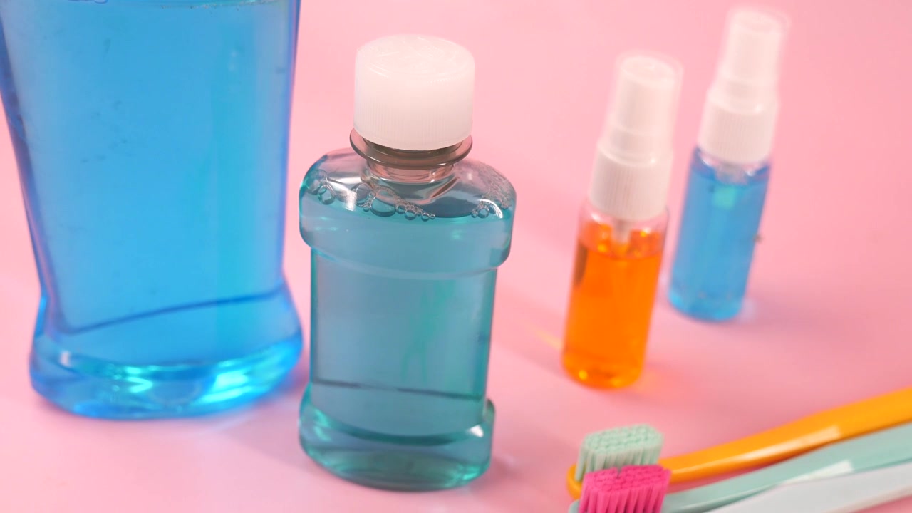 Collutorio, flaconi spray e spazzolini da denti per l'igiene orale su sfondo rosa