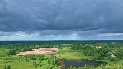 stratonimbus and stratus clouds over green vast countryside landscape with an aerial tilt down pull out shot, latvia