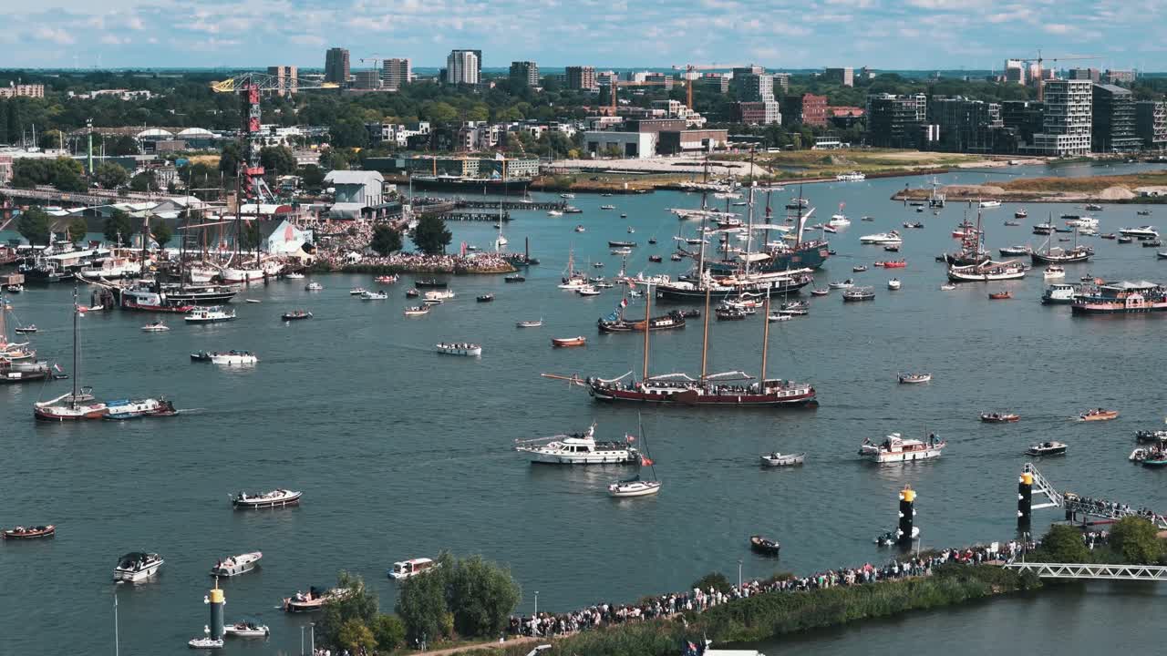 Aerial orbit left over crowd of sailboats during Amsterdam Sail Festival in sunny harbor