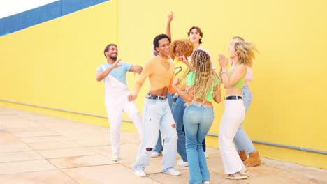 group of friends dancing in front of a yellow wall