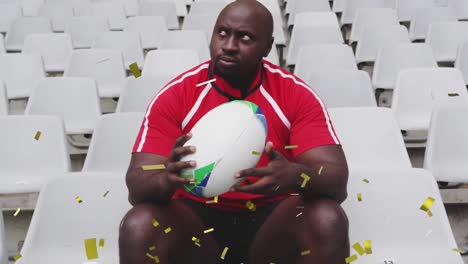 Animation-of-golden-confetti-falling-over-African-American-male-rugby-player-sitting