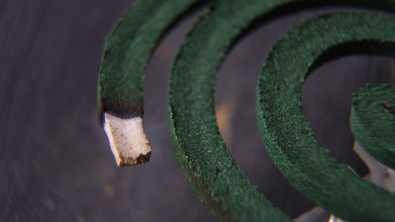 High-angle close-up of a burning mosquito coil against a dark background