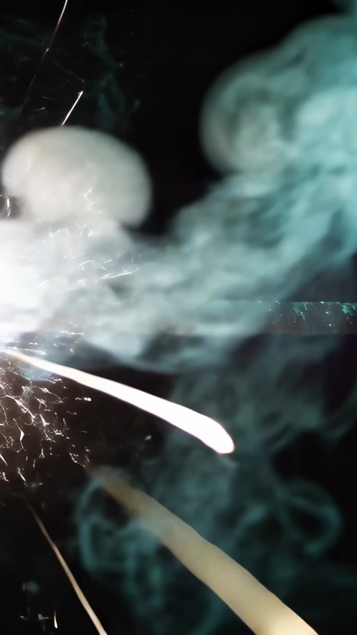 Ignition point emitting spark trails and teal smoke across night rail, embers fading for film