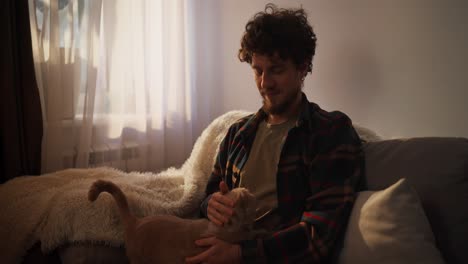 uomo che si rilassa con il gatto sul divano