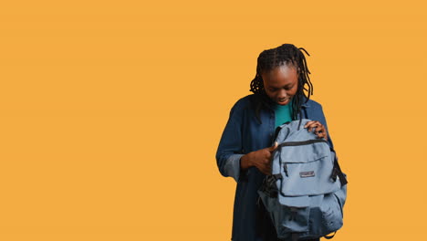 girl taking out business class materials out of rucksack, studio background