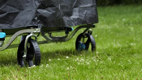 the wheels of a folded table tennis table cover on a grassy lawn - close up