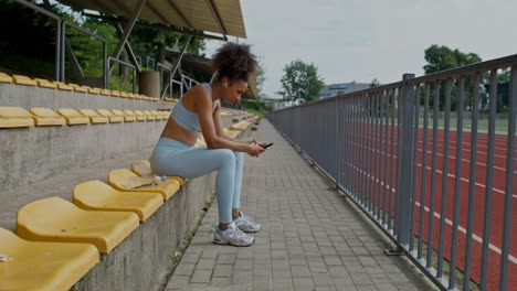 mujer descansando en las gradas del estadio, usando su teléfono