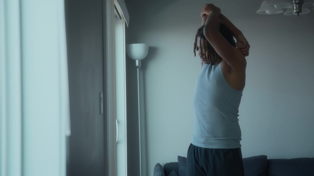 Un uomo che fa stretching accanto a una finestra a casa
