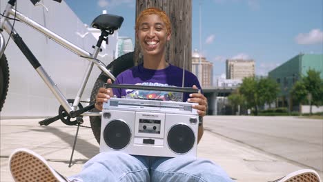 Plano-Medio-De-Una-Joven-Afroamericana-Contra-Una-Pared-Blanca-Escuchando-Un-Boom-Box