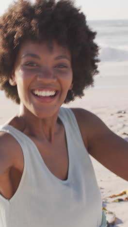 portrait of smiling african american woman holding hand on sunny beach