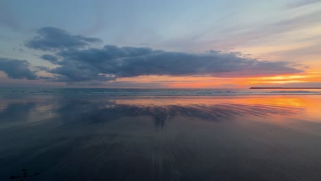 lapso de tiempo de nubes moviéndose hacia una playa tranquila con una espectacular puesta de sol sobre el horizonte