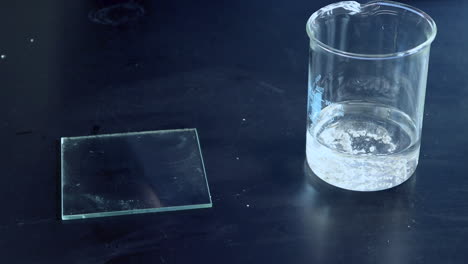 el calcio metálico se agrega a un vaso de precipitados de vidrio y reacciona vigorosamente con agua para producir hidrógeno inflamable que se enciende repetidamente con una férula ardiente