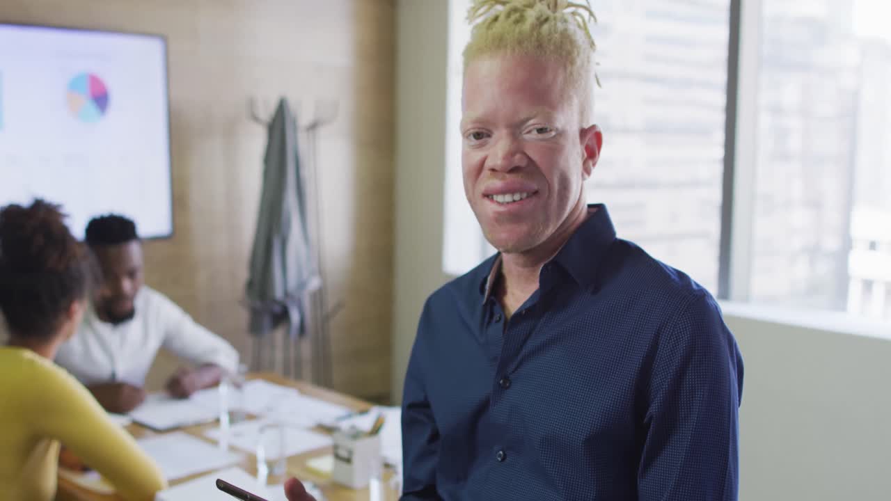 retrato de un feliz hombre de negocios albino afroamericano con una tableta en la oficina creativa