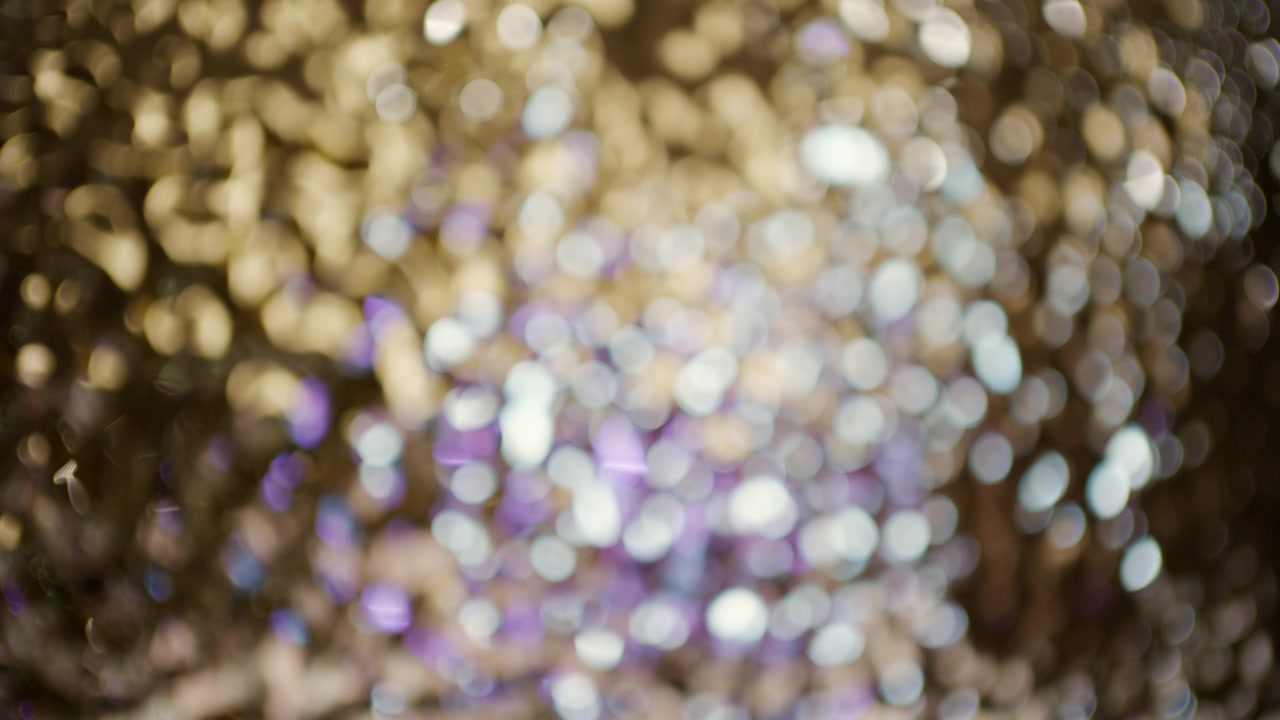 Abstract close up of golden, white, and purple bokeh lights with a soft glittering texture