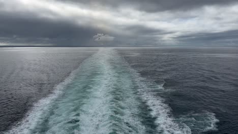 the wake behind a cruise ship in on a cold, cloudy, moody day at sea