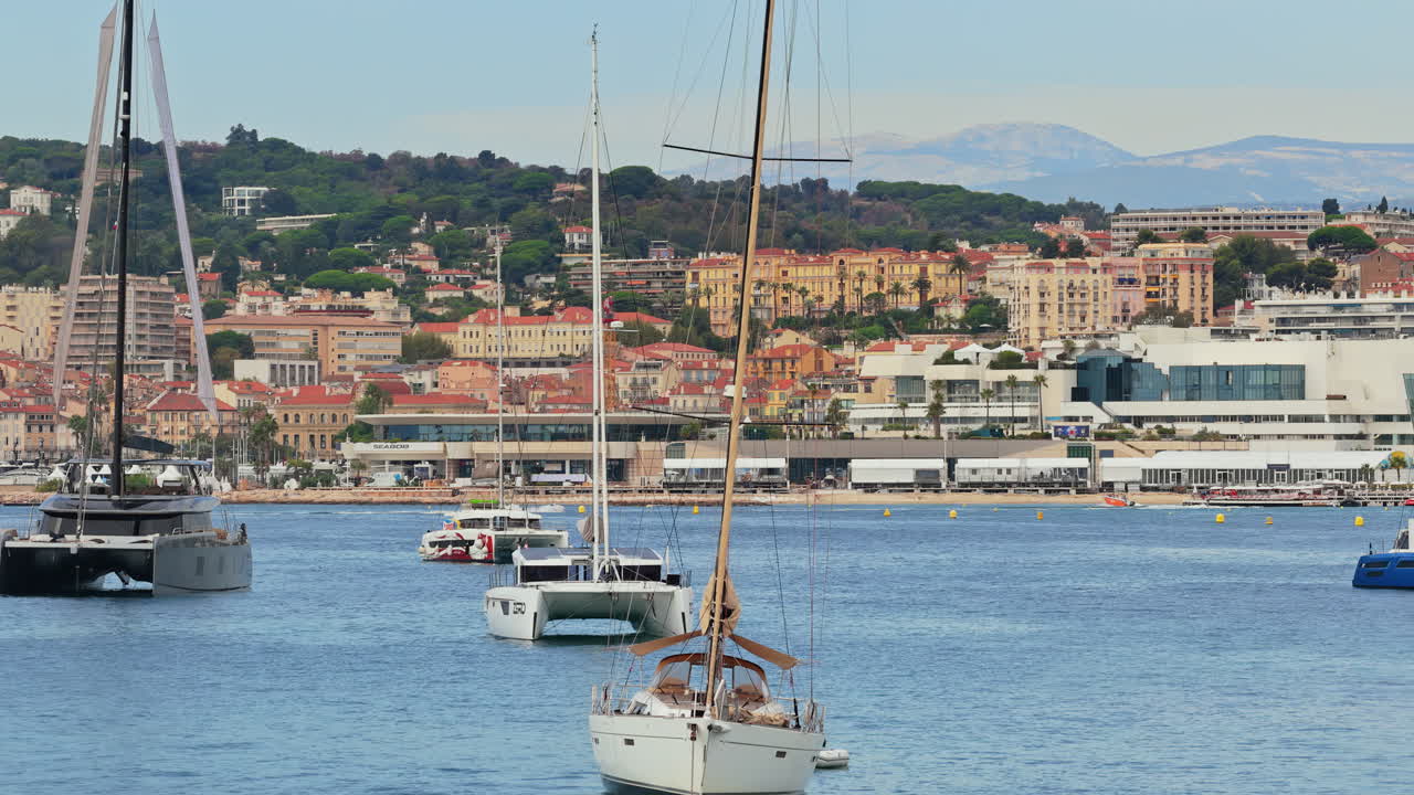 Aerial drone view of luxury yachts anchored offshore with the Palais des Festivals and Cannes city skyline in the background