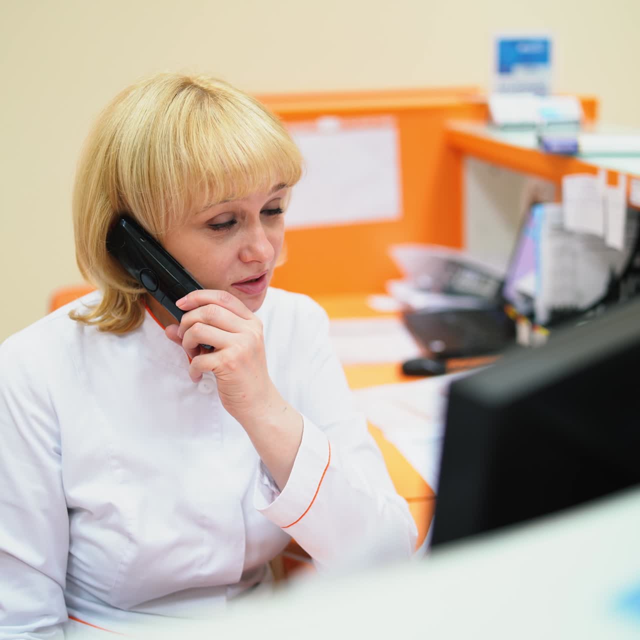 Kvinnelig resepsjonist snakker i telefonen på klinikk