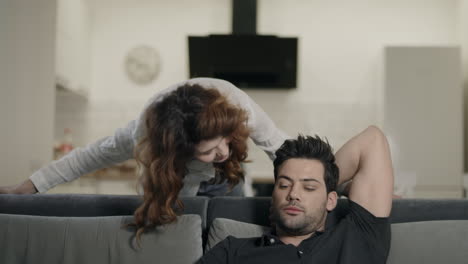 man looking backwards in living room at woman. happy couple smiling in living room.