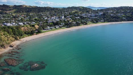 Gran-Playa-De-Oneroa-Con-Un-Océano-Tranquilo-En-La-Isla-Waiheke,-Nueva-Zelanda---Retroceso-Aéreo