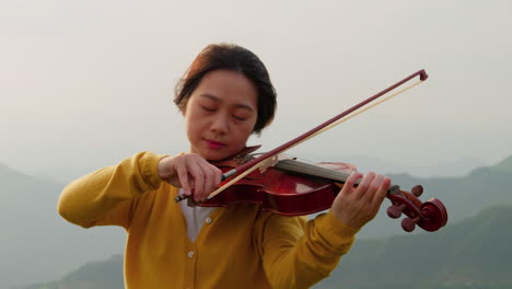 Slow-Motion-Shot,-Brunette-Woman-Playing-Violin-Amidst-Mountain-Scenery