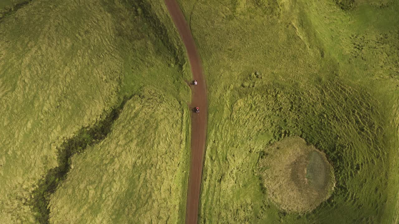Vista dall'alto con drone di quad su strada sterrata affiancata da vegetazione lussureggiante sull'isola di São Jorge, Azzorre, Portogallo