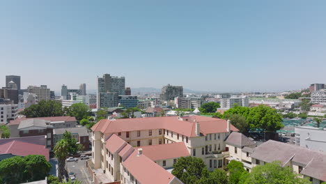 Aerial-ascending-footage-of-town-development-in-large-city-on-sunny-day.-Houses-with-red-roof-and-multistorey-buildings.-Cape-Town,-South-Africa