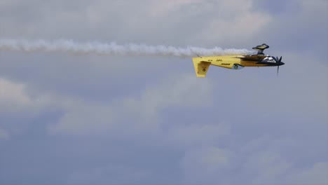 volando un avión acrobático al revés dejando un rastro de humo blanco detrás