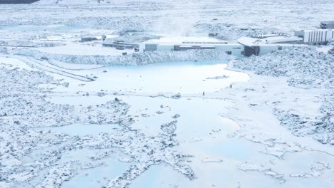 people walking in snow at blue lagoon pools outside of spa, aerial