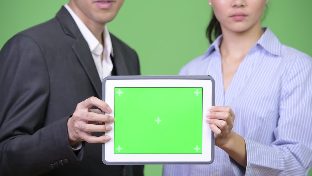 Young Asian business couple showing digital tablet together