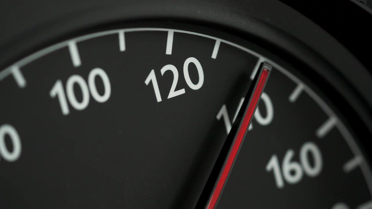 Close-up of a car speedometer with a red needle indicating high speed, with blurred blue police lights in the background. Concept image for speeding, traffic violations, police pursuit, emergency resp