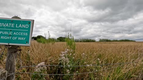 warning sign on rural field, cloudy sky, restricted access