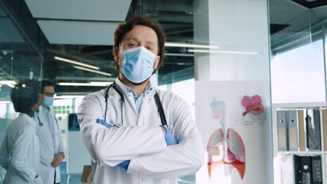 caucasian male doctor wearing medical mask looking at camera in hospital office