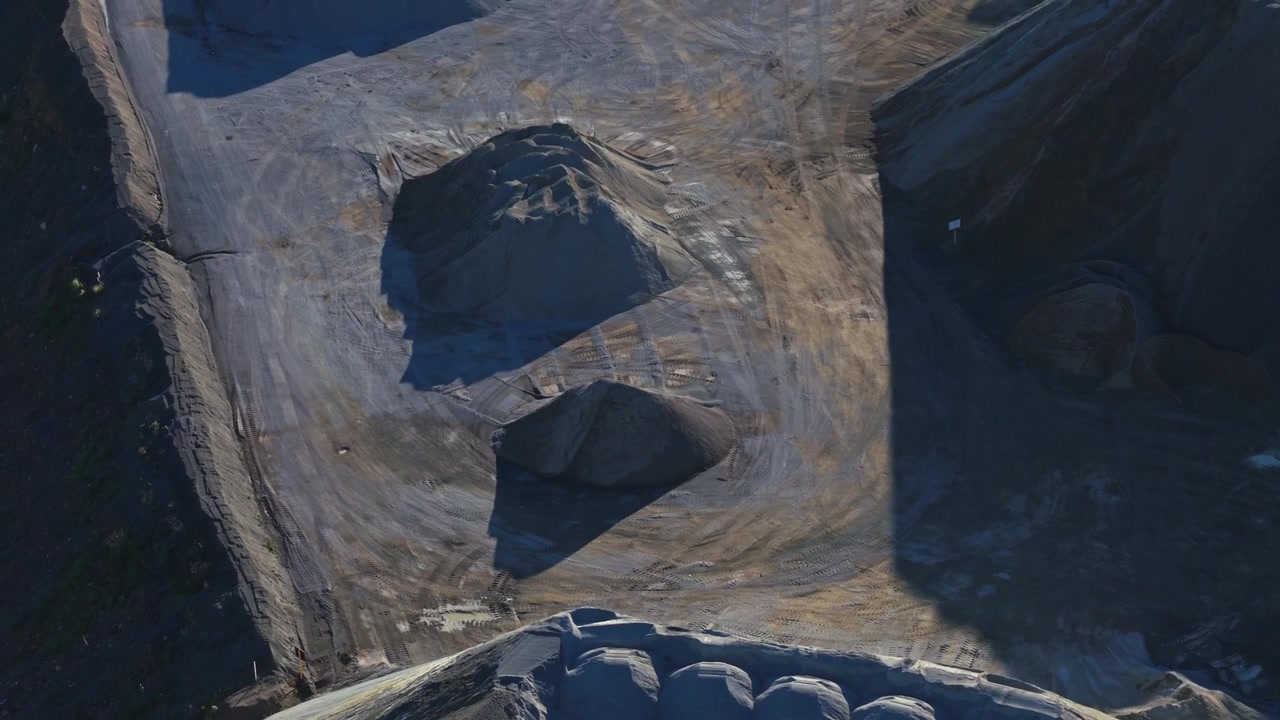 Drone video captures the sprawling Montrose Quarry in Melbourne, showcasing massive mounds, textured earth, sharp shadows, and industrial patterns under strong, perfect for construction themes.