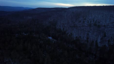 aerial drone video footage of nightfall in the snowy appalachian mountains during winter, in the catskill mountains sub-range