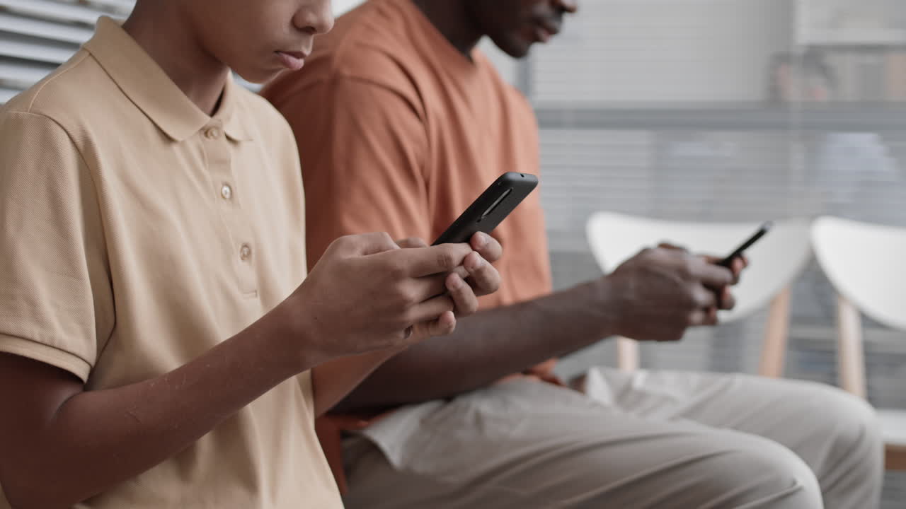 personas irreconocibles que usan teléfonos inteligentes sentadas en el interior