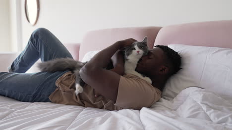 dueño de mascota con su gato en la cama
