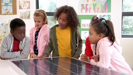 school children exploring solar panel in classroom, learning about renewable energy