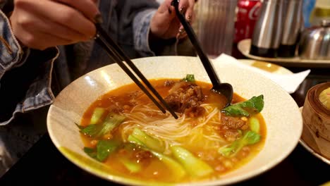 person enjoying ramen soup with chopsticks