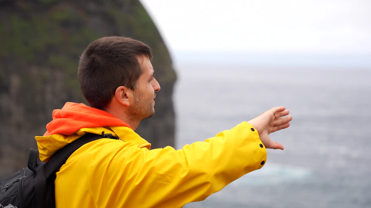 Uomo con giacca gialla che indica e spiega ciò che vede con movimenti delle mani, Faial, Azzorre