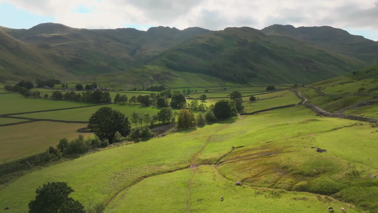 Valle di Great Langdale con volo lento verso le montagne, Crinkle Crags e chiazze di sole. Estate. Lake District, Cumbria, Regno Unito
