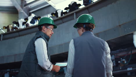 Livestock-specialists-working-automatic-milking-machinery-with-tablet-computer.