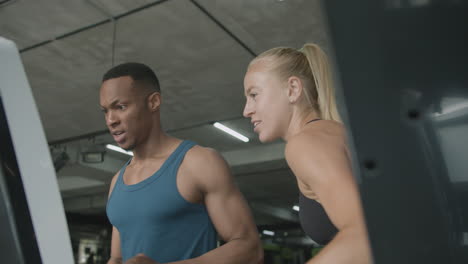 una vista de cerca de una mujer caucásica y un atlético afroamericano en el gimnasio.