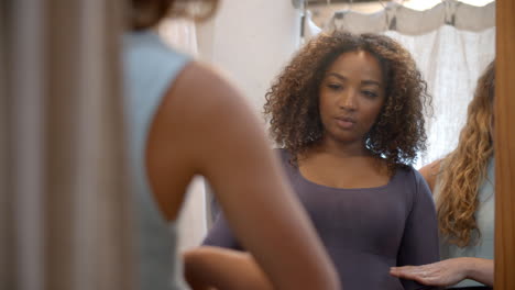 woman in changing room with friend trying on dress, close up